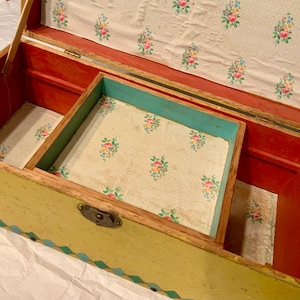 May include: A vintage wooden storage chest with a yellow exterior, blue and green trim, and a floral patterned lining. The chest has a brass latch and a divided interior.