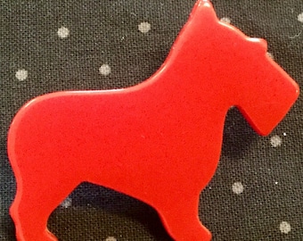 Könnte beinhalten: Eine leuchtend rote Plastik-Silhouette eines Hundes, möglicherweise ein Terrier, mit einem einfachen Design. Der Hund blickt nach rechts und hat einen langen Schwanz.