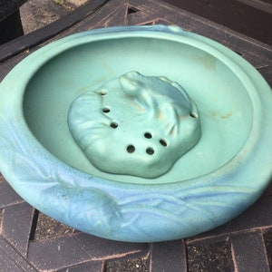 May include: A light blue ceramic frog planter with a textured surface and a frog design. The planter has a small hole in the bottom for drainage.