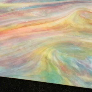 May include: A sheet of iridescent glass with a swirling pattern of yellow, pink, blue, and green colors.