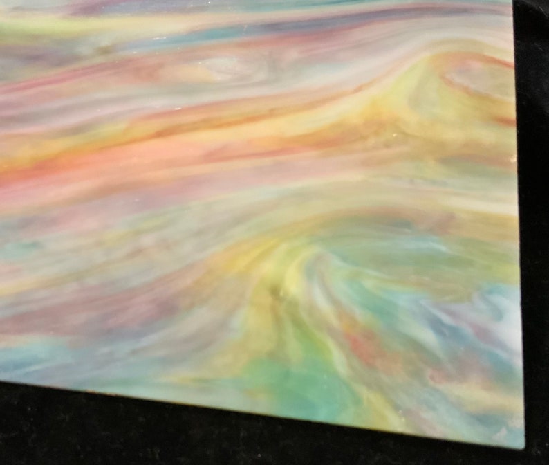 May include: A sheet of iridescent glass with a swirling pattern of yellow, pink, blue, and green colors.