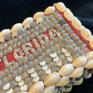 May include: A decorative box covered in various seashells. The box has a red interior and the word "LOVE" spelled out in small shells. The exterior is adorned with a variety of small, gray and white shells, with larger, cream-colored shells outlining the edges.