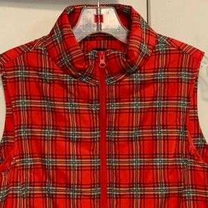 May include: A red, black, and yellow plaid sleeveless vest with a zipper closure.