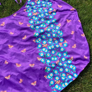 Op de afbeelding: Paarse stoffen rok met een bloemen- en vlinderprint. De rok heeft een strik in de taille en is gemaakt van een zacht, zijdeachtig materiaal.