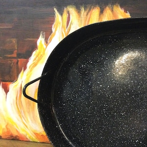 May include: A black enamel cast iron pan with a speckled finish. The pan is empty and has a white reflection in the bottom.