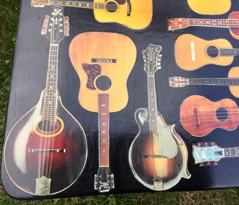 Op de afbeelding: Een verzameling vintage akoestische gitaren en mandolines met verschillende hout afwerkingen en inlays. De instrumenten zijn gerangschikt op een zwart oppervlak.