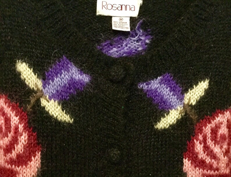 May include: Black fuzzy cardigan with a floral design. The flowers are pink, red, purple, and yellow. The cardigan has a button closure and the label "Rosanna" is visible.