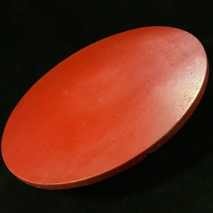 May include: A solid red round wooden tray. The tray is smooth and has a glossy finish.