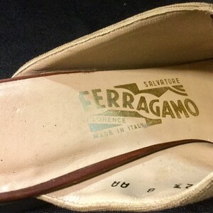 May include: Close-up of the inside of a beige shoe with a brown leather trim. The shoe is labelled "Salvatore Ferragamo Florence Made in Italy" in gold lettering.