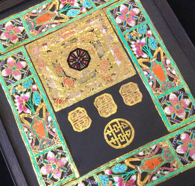 May include: A framed artwork with a black background and intricate gold and green paper cutouts. The artwork features a central square with a gold background and a black and gold design. The square is surrounded by four smaller gold squares with Chinese characters. The artwork is framed in a black frame.