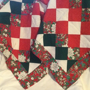 May include: A red, white, and green patchwork quilt with a floral pattern. The quilt is made of squares and has a border of red, white, and green flowers.