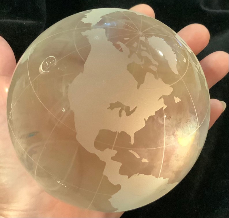Op de afbeelding: Een matglazen globe met een gedetailleerde gegraveerde wereldkaart. De globe is helder en heeft een lichte gele tint.