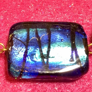 May include: A close-up of a blue and green glass bead necklace with gold accents. The beads are iridescent and have a textured surface.