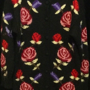 May include: Black cardigan sweater with a floral pattern of pink, red, and purple roses. The sweater has a button closure and the label "Rosanna" is visible on the front.