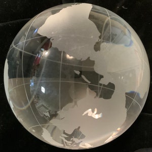 Op de afbeelding: Een heldere glazen globe met een gematteerde gegraveerde wereldkaart. De globe is een decoratief stuk met een gematteerde afwerking.