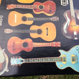 Op de afbeelding: Een verzameling van acht verschillende gitaren, waaronder een mandoline, een ukelele en een elektrische gitaar. De gitaren zijn gerangschikt op een zwart oppervlak en zijn allemaal in verschillende tinten bruin, blauw en natuurlijk hout.