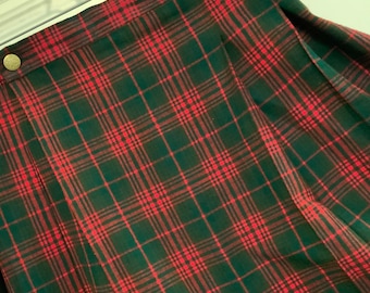 May include: A red and green plaid skirt with a pleated design. The skirt has a high waist and a button closure at the top.