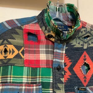 May include: A patchwork shirt with a variety of patterns and colors, including plaid, geometric, and tribal designs. The shirt features a button-down front, a collar, and the Polo Lauren label.