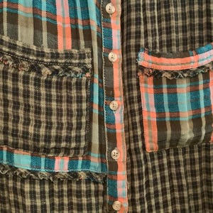 May include: A plaid shirt with a patchwork design. The shirt has two pockets with frayed edges and a button-up front.