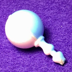 Pode incluir: Um chocalho de beb&ecirc; de pl&aacute;stico branco e azul claro com uma cabe&ccedil;a redonda e uma al&ccedil;a.