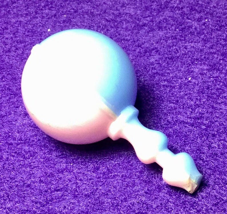 Pode incluir: Um chocalho de beb&ecirc; de pl&aacute;stico branco e azul claro com uma cabe&ccedil;a redonda e uma al&ccedil;a.