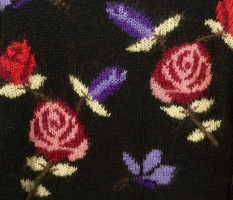 May include: Black knitted fabric with a floral pattern. The pattern features red, pink, and purple flowers with yellow stems and leaves.