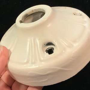 Puede incluir: Plafón de techo de cerámica blanca con un diseño decorativo y dos agujeros para el cableado.