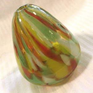 May include: A green, yellow, white, and red glass vase with a swirl pattern.