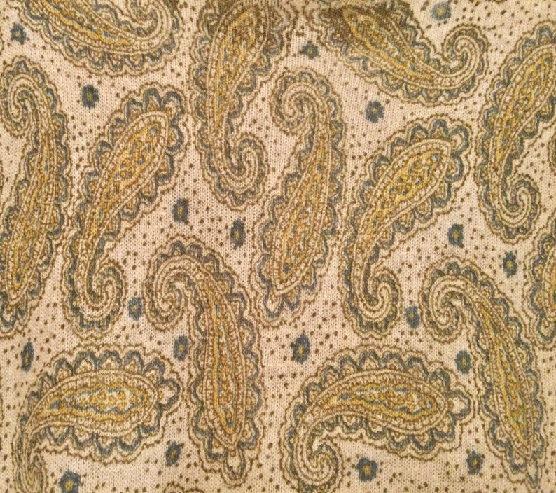 May include: A beige fabric with a paisley pattern in shades of brown and gray.