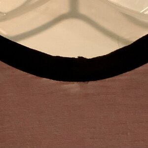 May include: A sleeveless top with a black trim around the neckline. The top is made of a soft, textured fabric.