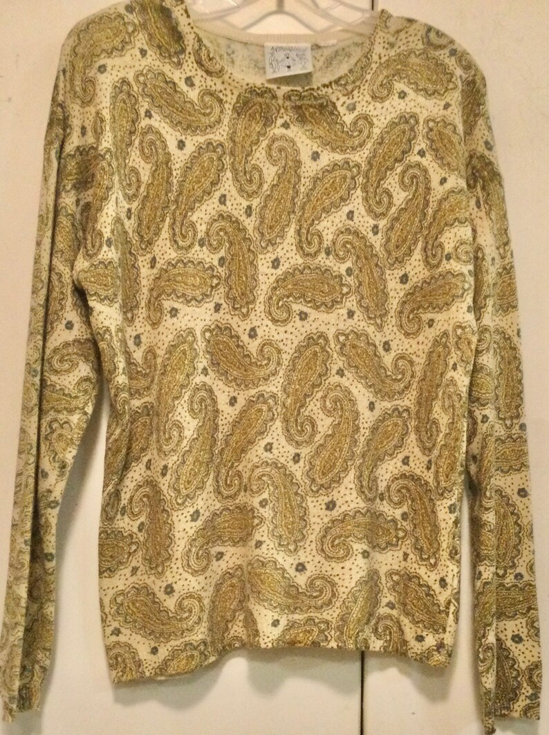 May include: A long-sleeved sweater with a paisley pattern in shades of gold and cream.