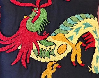 May include: A colorful rooster embroidered on a black pillow. The rooster is made of red, yellow, green, and blue yarn. The rooster's tail feathers are red, and its body is yellow and green.