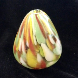 May include: A colorful, teardrop-shaped glass art piece. The glass is swirled with streaks of yellow, red, green, and white. The top has a small opening. The object is set against a black background.