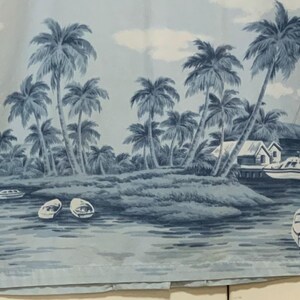 May include: Light blue button-down shirt featuring a tropical island scene. The print includes palm trees, boats, and small buildings. The shirt has a classic collar and long sleeves.