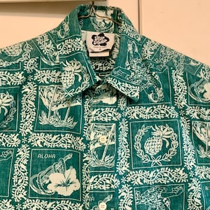 May include: Green button-up shirt with a white tropical print featuring pineapples, cocktails, and the word "Aloha." The shirt has a collar and a tag that reads "Aloha Kattie."