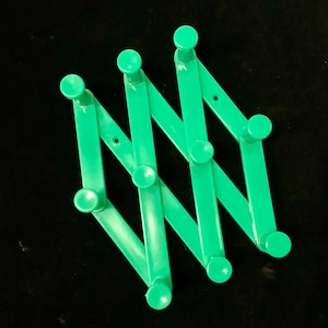 May include: A green plastic expandable coat rack with eight hooks. The rack is folded in a zig-zag pattern.