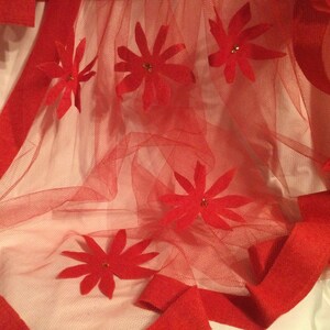 May include: Red tulle fabric with red felt flowers. The flowers have a center embellishment.