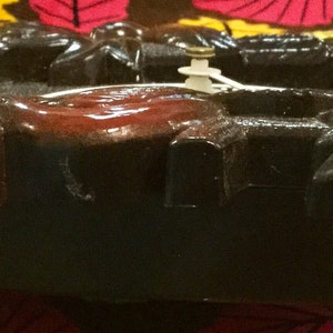 Op de afbeelding: Een donkerbruine houten koekoeksklok met ingewikkelde houtsnijwerk van bladeren en bloemen. De wijzerplaat van de klok is zichtbaar met Romeinse cijfers en een slinger die zwaait.