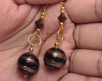 May include: A pair of gold dangle earrings with black and gold striped round beads and gold crystal beads.
