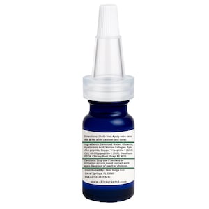 Op de afbeelding: Een kleine, donkerblauwe huidverzorgingsproductfles met een witte druppelkop. Het etiket bevat productinstructies, ingredi&euml;nten en waarschuwingen. Voor dagelijks gebruik, na reiniging en toning. Product van Skin Surge LLC.