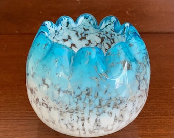 May include: A decorative glass bowl with a wavy rim. The bowl features a gradient of colors, transitioning from a bright turquoise at the top to white at the base. The glass has a speckled pattern of white and gray throughout.
