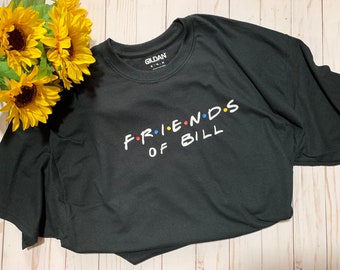 May include: Black t-shirt with the text "FRIENDS OF BILL" in a white font with colorful dots. The text is styled to look like the "Friends" logo.