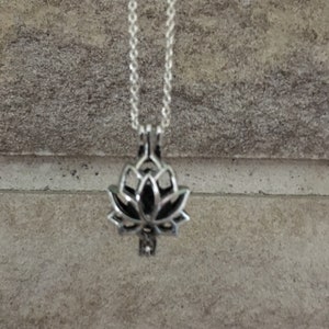 Op de afbeelding: Een zilveren ketting met een zilveren lotusbloem hanger. De hanger is open en lijkt een bedel of een medaillon te zijn.