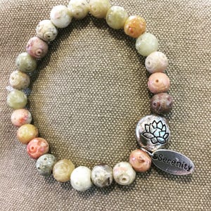 May include: A multi-colored stone bracelet with a silver charm featuring a lotus flower and the word "Serenity".