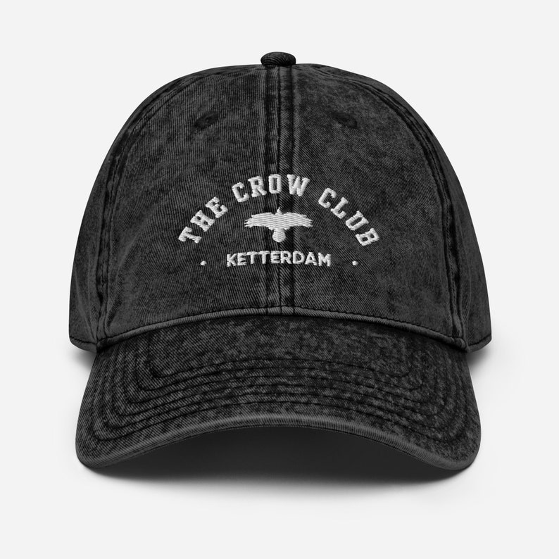 May include: A black vintage washed cotton baseball cap with white embroidery that reads "The Crow Club. Ketterdam."