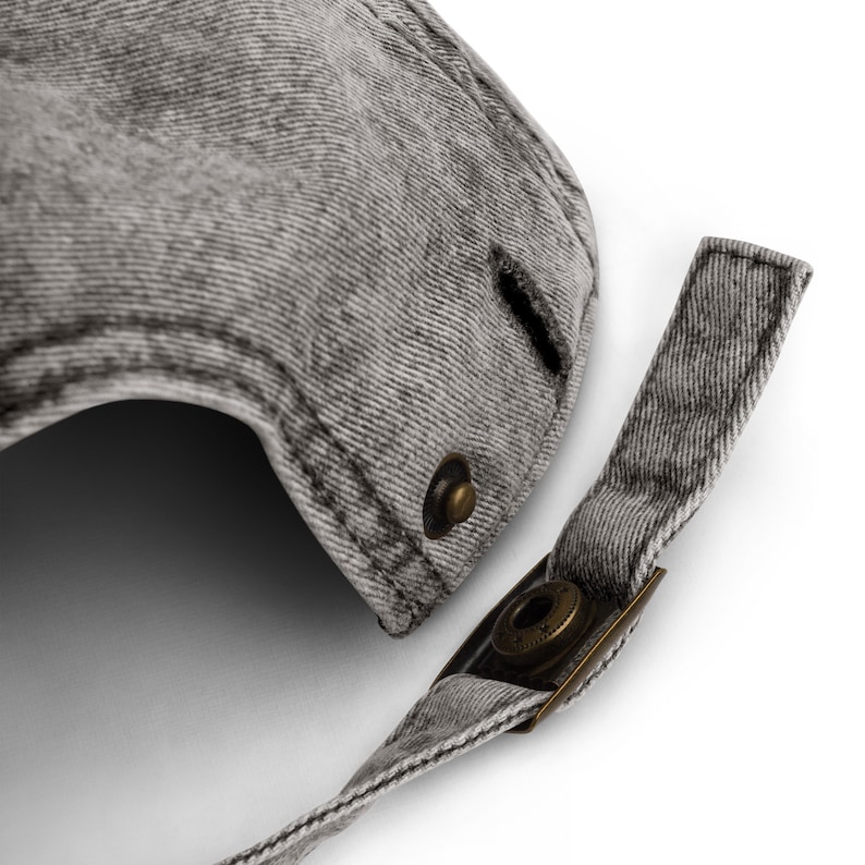 May include: A gray denim baseball cap with a metal adjustable strap and buckle. The cap has a distressed look and a small hole in the crown.