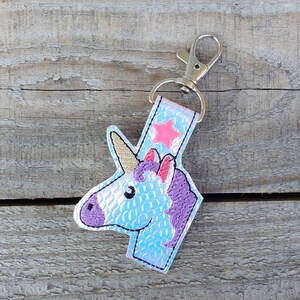 May include: A light blue iridescent unicorn keychain with a pink star and a silver key ring.