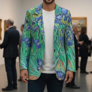 May include: A green and blue floral print blazer with a white t-shirt and dark blue jeans. The blazer features a vibrant design of irises and foliage. The person is standing in an art gallery.