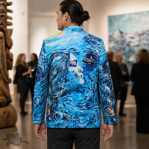 Op de afbeelding: Een blazer met een levendige blauwe artistieke print van een menselijk gezicht, kolkend water en een kleine boot. Het jasje heeft lange mouwen, een kraag en een gestructureerde pasvorm met een gedetailleerd schilderachtig ontwerp op de rug.