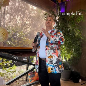 May include: A blazer featuring a vibrant, multi-colored graffiti-style print with black, red, blue, and yellow accents over a white base. The garment is worn over a plain white t-shirt and dark trousers. The text "Example Fit" appears in the corner.